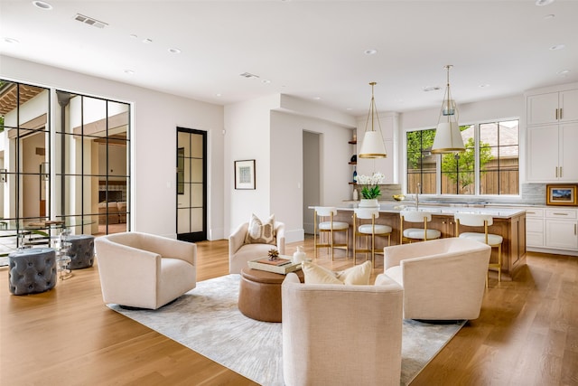 living area with recessed lighting, baseboards, visible vents, and light wood finished floors