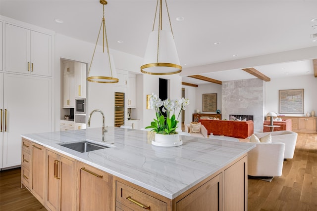 kitchen with a kitchen island with sink, open floor plan, a sink, and wood finished floors