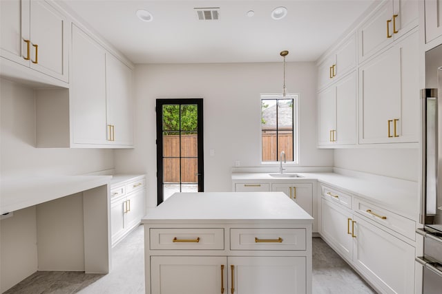 kitchen with a sink, light countertops, white cabinetry, decorative light fixtures, and visible vents