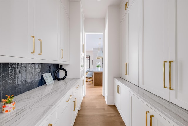 bar with light wood-style floors and tasteful backsplash