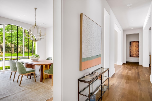 corridor with wood finished floors and a chandelier