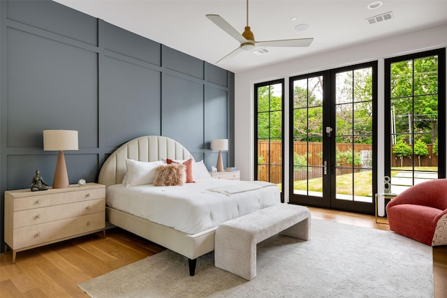 bedroom with access to exterior, a decorative wall, wood finished floors, and visible vents