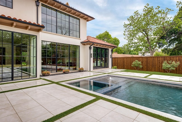rear view of property with fence, stucco siding, a patio area, and a tile roof