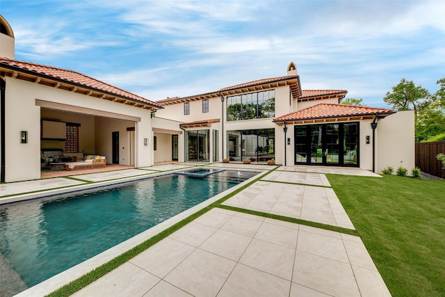 rear view of property featuring fence, a tile roof, stucco siding, a patio area, and a yard