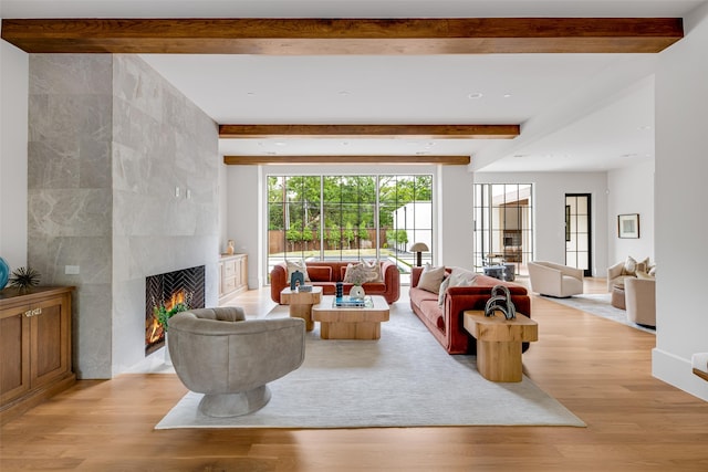 living area featuring recessed lighting, a large fireplace, beam ceiling, and light wood-style floors