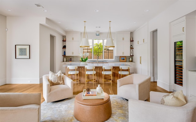 living room featuring recessed lighting, baseboards, visible vents, and light wood-style floors