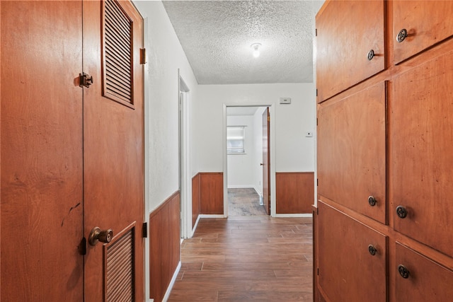 1733 Ransom Ter, Fort Worth, TX 76112 - hall featuring wood finished floors, wood walls, a textured ceiling, and a wainscoted wall