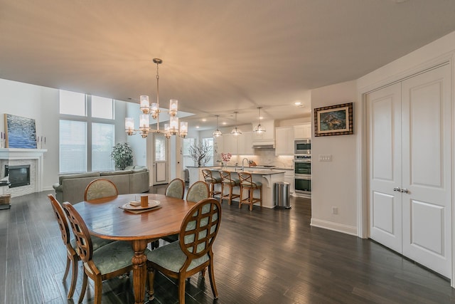 6256 Whitebrush Pl, Fort Worth, TX 76123 - dining area featuring an inviting chandelier, dark wood finished floors, a glass covered fireplace, and baseboards