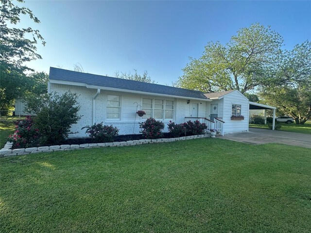 ranch-style house with a carport, driveway, brick siding, and a front yard