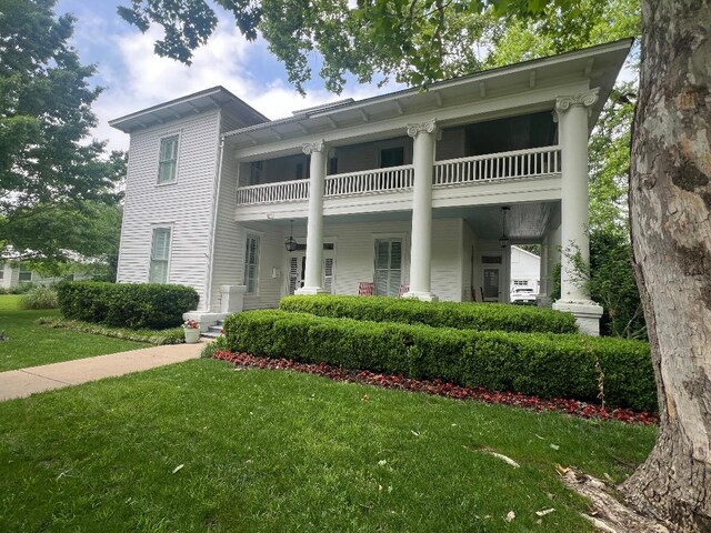 view of front of property featuring a front lawn and a balcony