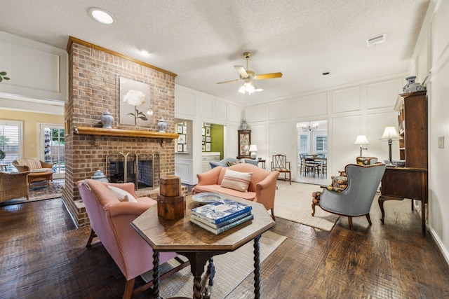 living area featuring ceiling fan with notable chandelier, a decorative wall, wood finished floors, and visible vents