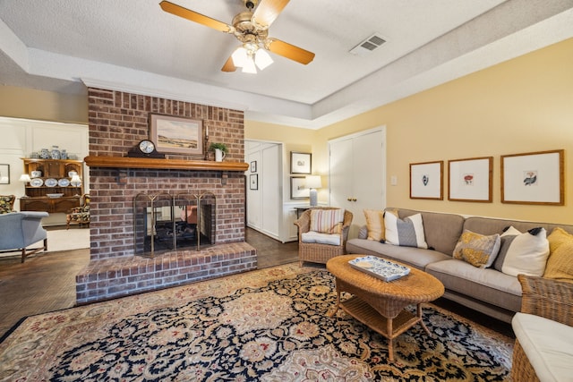 living room with visible vents, a raised ceiling, ceiling fan, and a fireplace