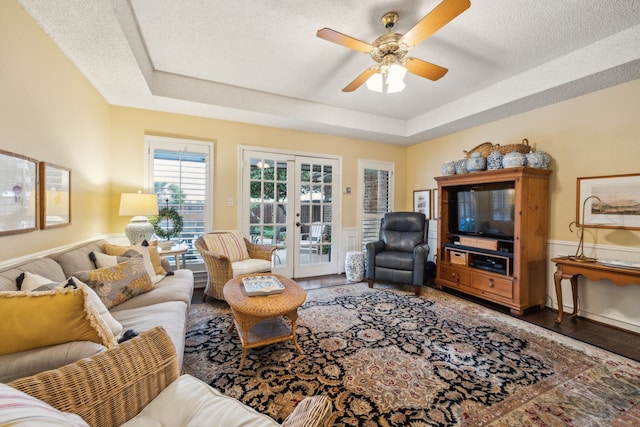 living room with french doors, a textured ceiling, a tray ceiling, and ceiling fan