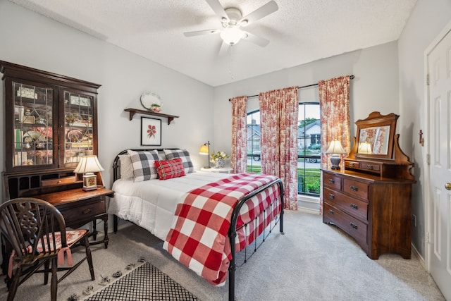 bedroom with a ceiling fan, a textured ceiling, and light carpet