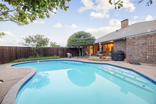view of swimming pool featuring a fenced in pool, grilling area, a fenced backyard, and a patio area