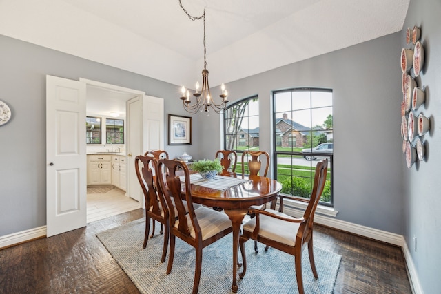 dining space with baseboards, an inviting chandelier, and wood finished floors