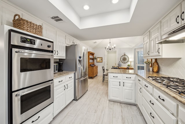 kitchen featuring stainless steel appliances, a chandelier, white cabinetry, and a peninsula