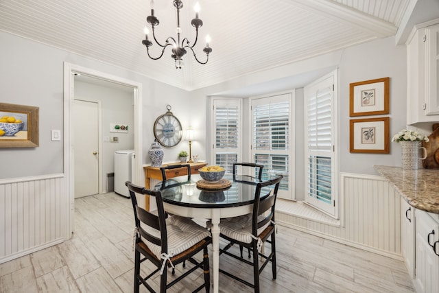 dining area with washer / dryer, an inviting chandelier, light wood finished floors, and a wainscoted wall
