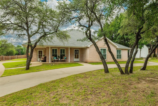 ranch-style house featuring fence, concrete driveway, brick siding, and a front yard