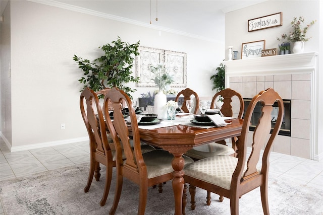 dining space featuring crown molding, baseboards, light tile patterned floors, and a tile fireplace