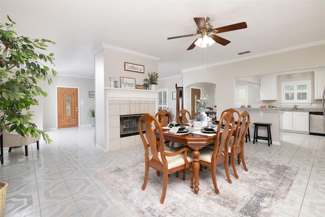 dining room featuring visible vents, crown molding, a fireplace, and ceiling fan