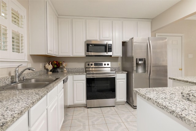 kitchen featuring a sink, appliances with stainless steel finishes, light tile patterned flooring, and white cabinets