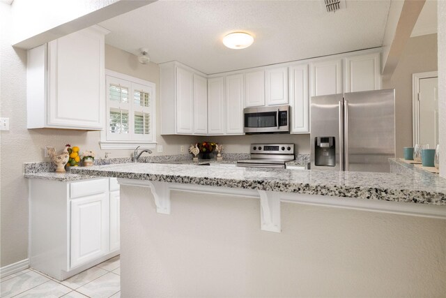 kitchen with white cabinets, stainless steel appliances, visible vents, and light stone counters