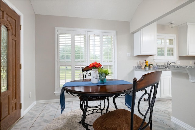 dining room with baseboards, light tile patterned flooring, and lofted ceiling