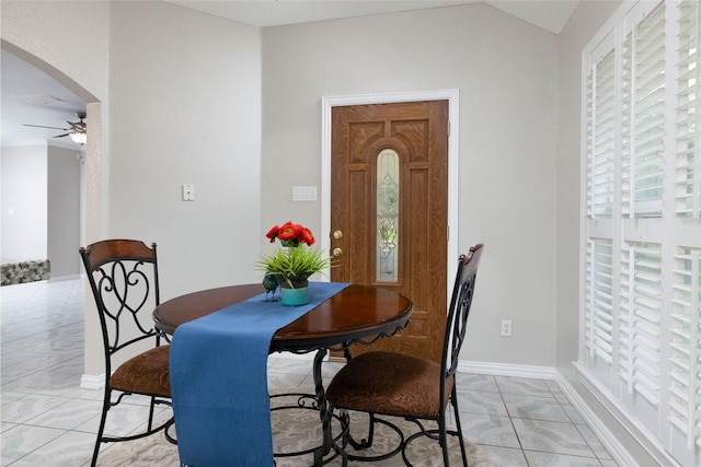 dining space featuring lofted ceiling, baseboards, ceiling fan, arched walkways, and light tile patterned floors