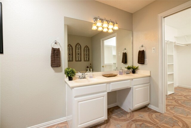 full bathroom featuring double vanity, a sink, tile patterned floors, and a spacious closet