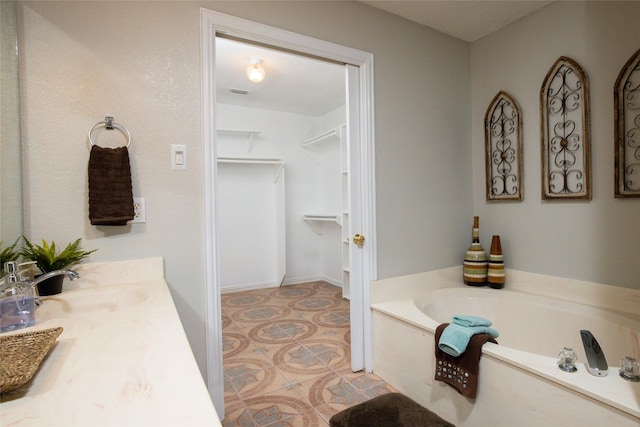 full bathroom featuring a spacious closet, a garden tub, and vanity