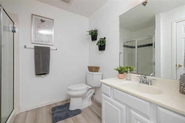 bathroom with vanity, wood finished floors, toilet, baseboards, and a stall shower