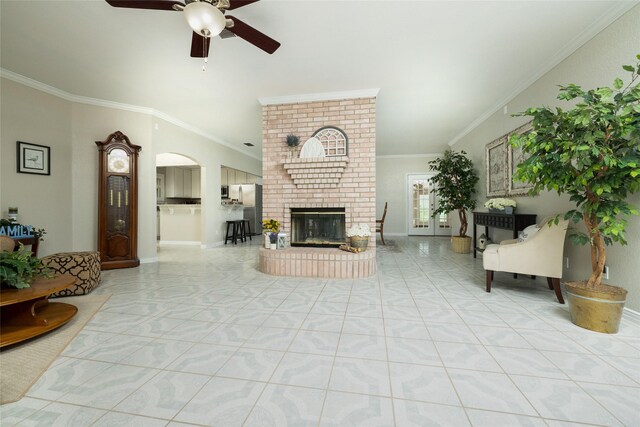 living room featuring crown molding, ceiling fan, a fireplace, arched walkways, and light tile patterned floors