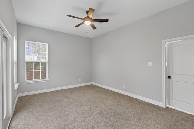 carpeted spare room with baseboards and a ceiling fan