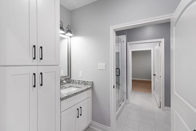 bathroom featuring vanity, baseboards, tile patterned flooring, and a stall shower