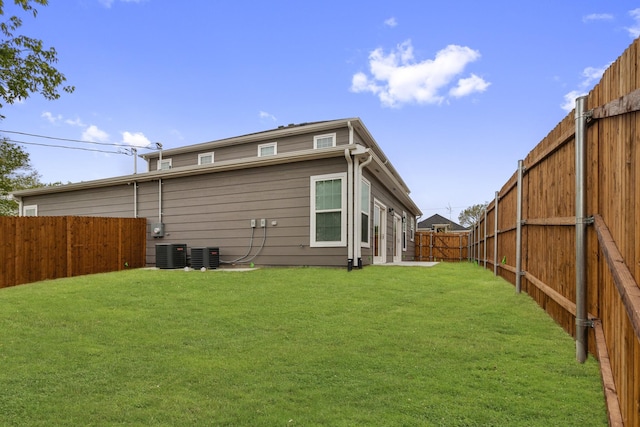 back of house featuring a lawn, cooling unit, and a fenced backyard