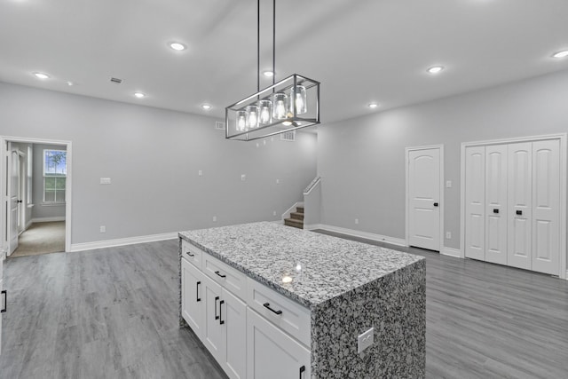 kitchen with white cabinetry, baseboards, a center island, and light wood-type flooring