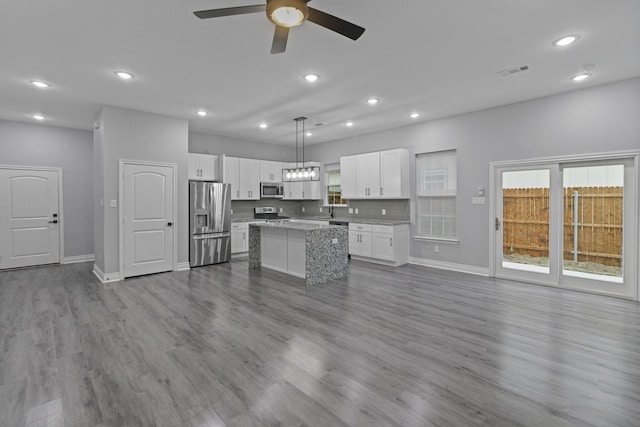 kitchen with stainless steel appliances, baseboards, a ceiling fan, a kitchen island, and visible vents