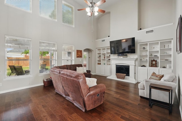 living area with arched walkways, ceiling fan, visible vents, and a towering ceiling