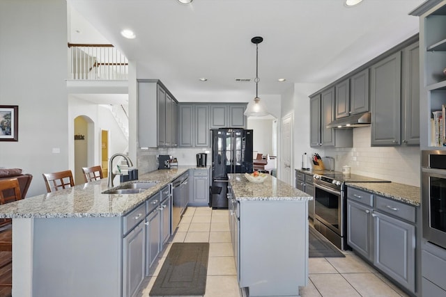 kitchen with a kitchen island, appliances with stainless steel finishes, a sink, a peninsula, and under cabinet range hood
