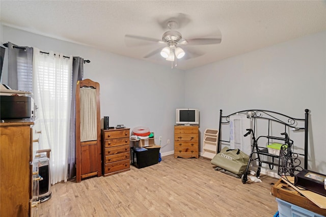 bedroom featuring a textured ceiling, ceiling fan, and light wood-style flooring