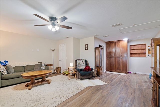 living area featuring ceiling fan, attic access, wood finished floors, and visible vents