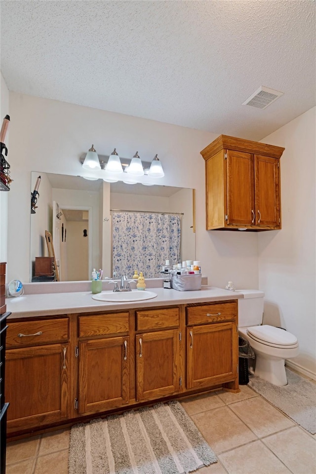 full bath with visible vents, vanity, toilet, a textured ceiling, and tile patterned floors