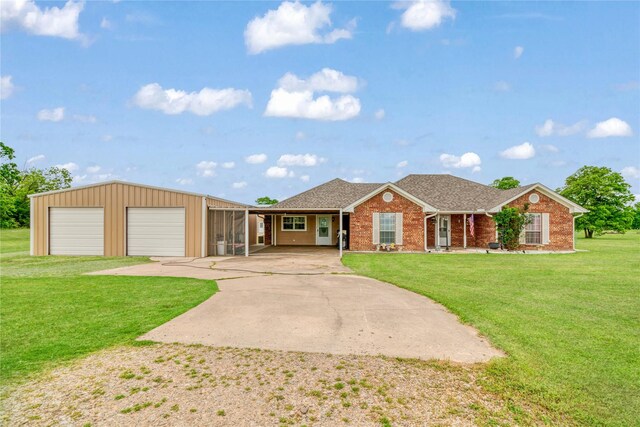 ranch-style house with roof with shingles, a front lawn, brick siding, a detached garage, and concrete driveway