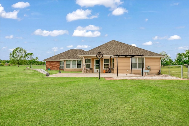 rear view of property featuring a lawn, a shingled roof, a patio area, and fence