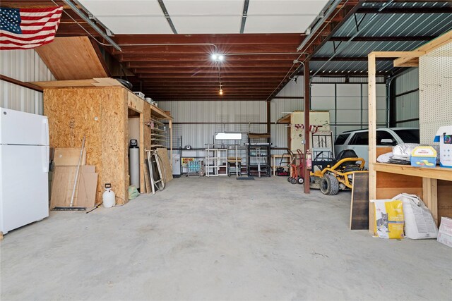 garage with freestanding refrigerator and metal wall