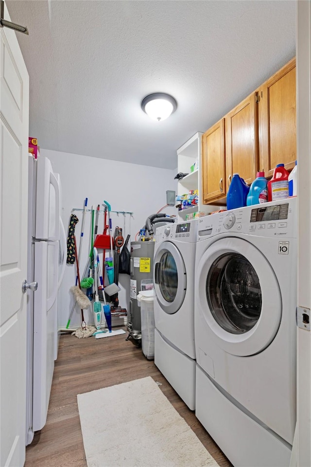 laundry room featuring cabinet space, washer and dryer, a textured ceiling, light wood-type flooring, and electric water heater