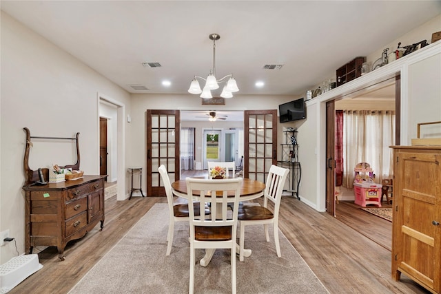 dining space with a notable chandelier, light wood-type flooring, and visible vents