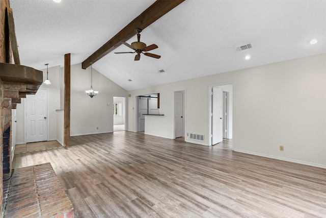 unfurnished living room featuring visible vents, ceiling fan with notable chandelier, a fireplace, and light wood-type flooring