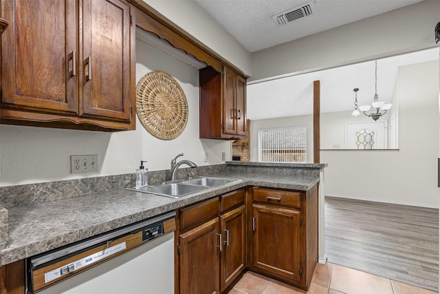 kitchen featuring visible vents, white dishwasher, a sink, and dark countertops